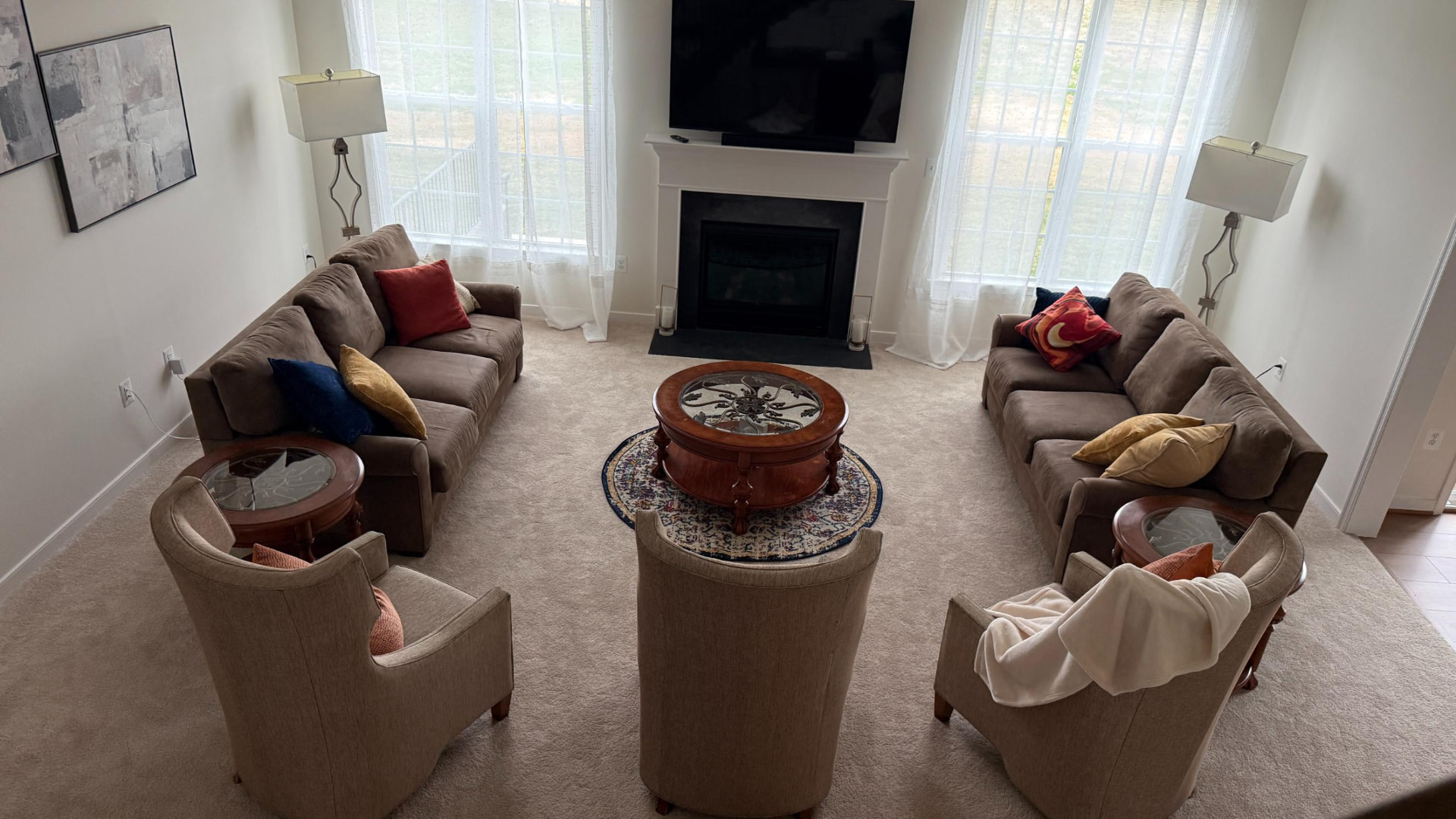 Wide view of the completed living room with paired sofas, fireplace and layered lighting