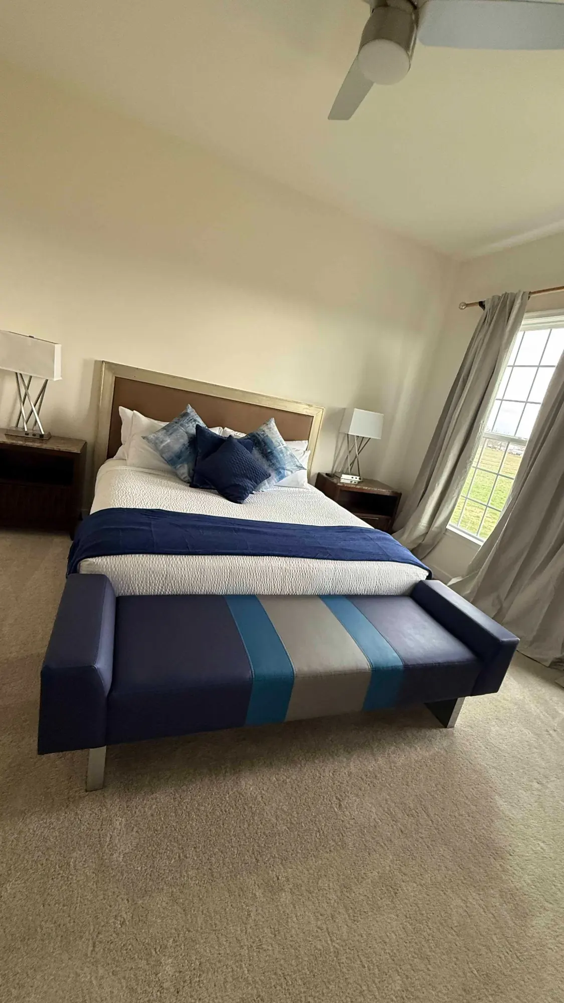 Guest bedroom styled with indigo bedding, layered pillows and a striped bench